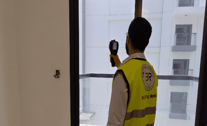 أحد مهندسي شركة بلدنغ رانك يقوم بفحص عقار في الإمارات حيث يقوم بفحص جودة العزل حول النوافذ